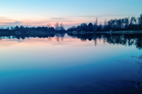Lago tranquilo al atardecer cerca de una casa para 6 personas en Eskebjerg, Dinamarca, con reflejos de árboles.