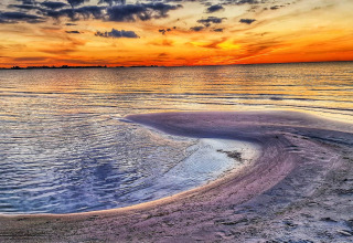 Impresionante puesta de sol en la playa de 6-Person Home en Eskebjerg, Dinamarca, con aguas tranquilas y cielo colorido.