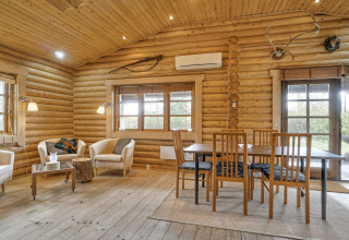 Helles Wohnzimmer in einer Blockhütte in Eskebjerg, Dänemark, mit Essbereich und gemütlichen Sesseln.