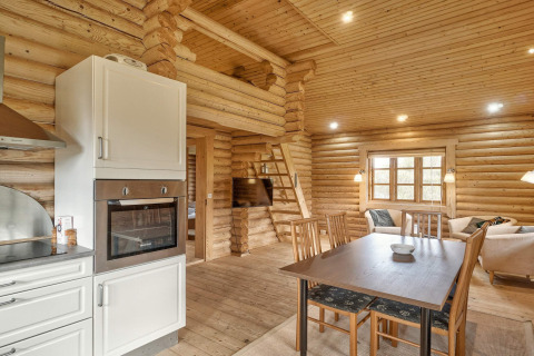 Interno di un lodge in legno a Eskebjerg, Danimarca, con tavolo da pranzo e soggiorno accogliente.