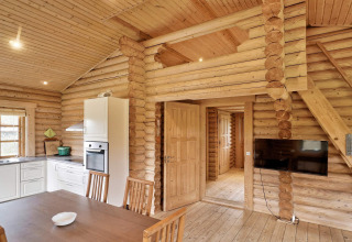 Blockhaus in Eskebjerg, Dänemark, zeigt modernes Küchen- und Essbereich mit Holzdekor und Fernseher.