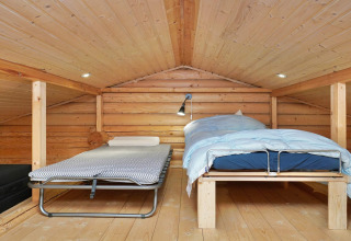 Zolderkamer in houten lodge met twee bedden en houtafwerking in 6-persoonshuis in Eskebjerg, Denemarken.