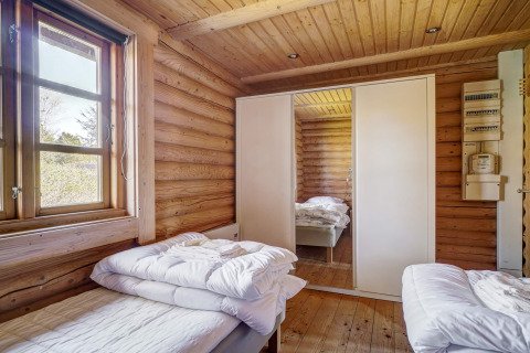 Chambre d'une cabane en bois du logement 6 personnes à Eskebjerg, Danemark, avec deux lits et une armoire à miroir.