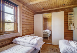 Slaapkamer in blokhut van 6-persoons huis in Eskebjerg, Denemarken met twee bedden en spiegelkast.