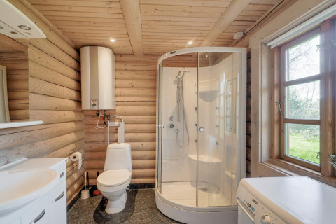 Badkamer in houten lodge met douche, toilet, wasmachine en groot raam in Eskebjerg, Denemarken.