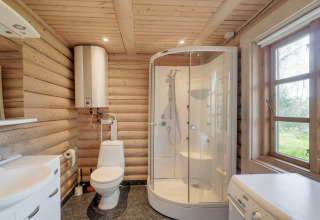 Holzbad mit Dusche, Toilette, Waschmaschine und großem Fenster in Eskebjerg, Dänemark.