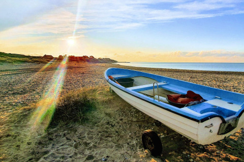 Barca pequeña en la playa al atardecer cerca de la casa de vacaciones para 6 personas en Melby, Dinamarca.