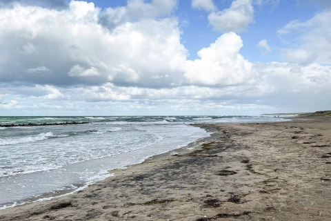 Rustig strand met wolkenlucht nabij Melby, Denemarken, gezien vanaf een 6-persoons vakantiehuis.