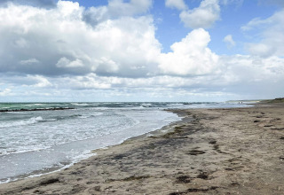 Spiaggia tranquilla e cielo nuvoloso vicino a Melby, Danimarca, vista da una casa vacanze per 6 persone.