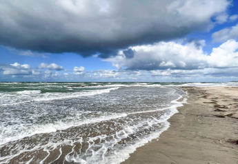 Golven aan de kust onder een bewolkte hemel nabij een 6-persoons vakantiehuis in Melby, Denemarken.