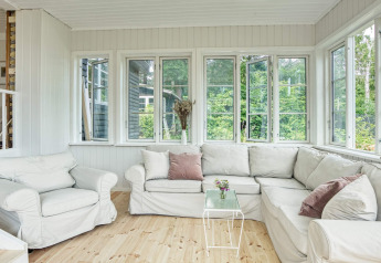 Salón luminoso y acogedor con sofás blancos y grandes ventanales en casa vacacional para 6 en Melby, Dinamarca.
