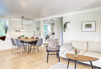 Salón luminoso y moderno en la casa de vacaciones para 6 personas en Melby, Dinamarca, con cocina abierta.