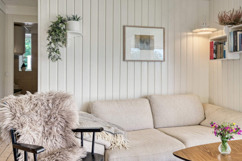 Knusse woonkamer in vakantiehuis in Melby, Denemarken, met zetel, boekenplank, planten en kunst aan de muur.