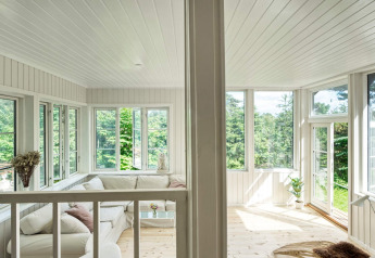 Heldere veranda in vakantiehuis voor 6 personen in Melby, Denemarken, met grote ramen en natuurzicht.