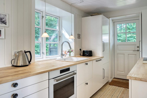 Cucina luminosa e moderna nella casa vacanza per 6 persone a Melby, Danimarca, con piano in legno.