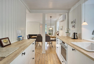 Cucina luminosa e zona pranzo in una casa vacanze per 6 persone a Melby, Danimarca, con decorazioni in legno.