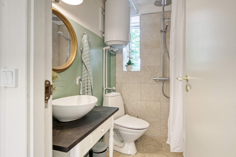 Baño moderno con lavabo, espejo, inodoro y ducha en una casa de vacaciones en Melby, Dinamarca.