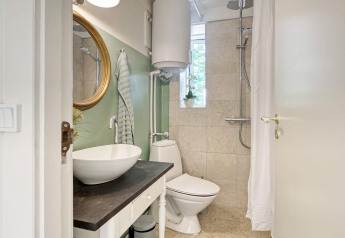 Modern badkamer met wastafel, spiegel, toilet en douche in een vakantiehuis in Melby, Denemarken.