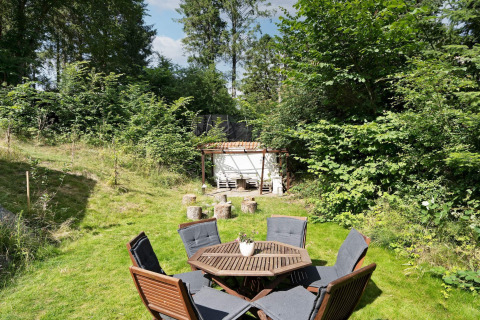 Zona de estar al aire libre con mesa, sillas y cabaña de jardín en casa vacacional en Melby, Dinamarca.