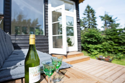 Buiten terras bij 6-persoons vakantiehuis in Melby, Denemarken, met wijnfles en glazen op het bankje.
