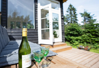 Terraza exterior de casa vacacional para 6 personas en Melby, Dinamarca, con botella de vino y copas.