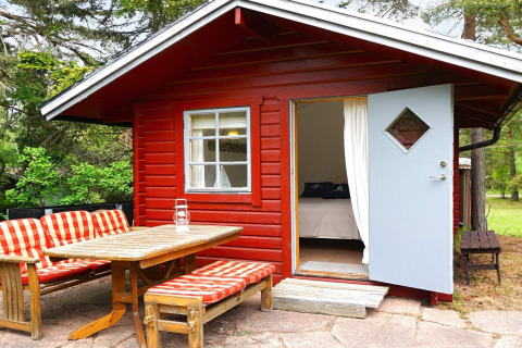 Rood houten chalet met open blauwe deur en tuinmeubels bij '6-persoons vakantiehuis in Mönsterås', Zweden.