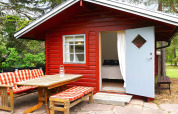 Rood houten chalet met open blauwe deur en tuinmeubels bij '6-persoons vakantiehuis in Mönsterås', Zweden.