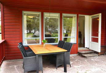 Terrasse extérieure avec table et chaises devant un chalet rouge pour six à Mönsterås en Suède.