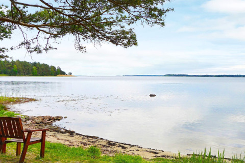 Vue paisible sur un lac avec un banc en bois et des arbres au bord de l’eau à Mönsterås, Suède.