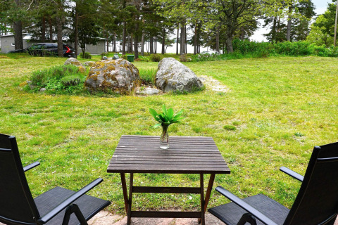 Twee stoelen en een tafel met een vaas bij het 6-persoons vakantiehuis in Mönsterås, Zweden, met uitzicht op groen.