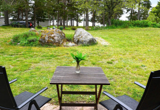 Due sedie e un tavolo con un vaso nella casa vacanze per 6 persone a Mönsterås, Svezia, vista sul giardino verde.