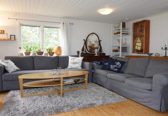Gezellige woonkamer in een vakantiehuis in Mönsterås, Zweden met grijze zetels en houten salontafel.