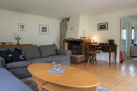 Woonkamer met grijze zetels, haard, houten tafel en bureau in vakantiewoning in Mönsterås, Zweden.