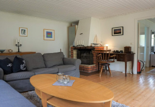 Stue med grå sofaer, pejs, træbord og skrivebord i feriebolig i Mönsterås, Sverige.
