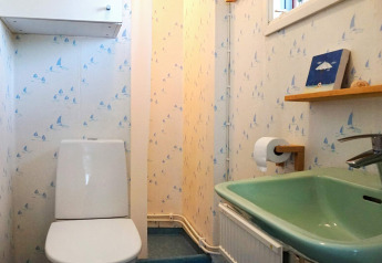 Heldere badkamer met toilet, groene lavabo en zeilbootbehang in een vakantiehuis in Mönsterås, Zweden.