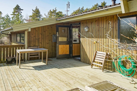 Houten terras met tafel en stoel bij Seaside Serenity lodge in Snogebaek, Denemarken, tussen het groen.