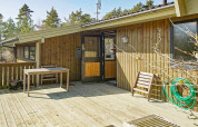 Houten terras met tafel en stoel bij Seaside Serenity lodge in Snogebaek, Denemarken, tussen het groen.