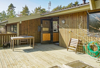 Houten terras met tafel en stoel bij Seaside Serenity lodge in Snogebaek, Denemarken, tussen het groen.