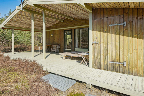 Udendørs terrasse på Seaside Serenity i Snogebaek, Danmark, med træbeklædning og skovomgivelser.