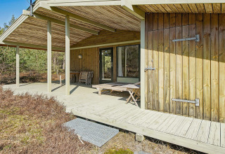 Terrasse en bois du lodge Seaside Serenity à Snogebaek, Danemark, entourée de nature et d’arbres verts.