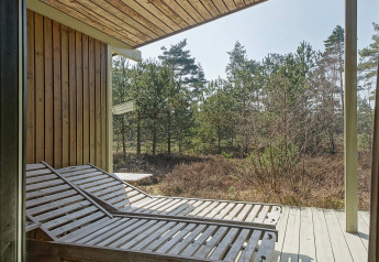 Zonneterras met houten ligstoelen bij Seaside Serenity in Snogebaek, Denemarken, zicht op het bos.