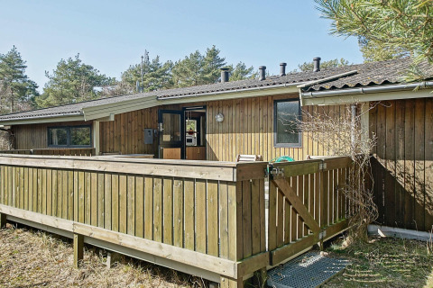 Udendørs billede af Seaside Serenity i Snogebaek, Danmark, med træterrasse og grønne omgivelser.