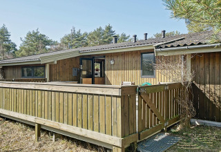 Vista exterior de Seaside Serenity en Snogebaek, Dinamarca, con terraza de madera y entorno natural.