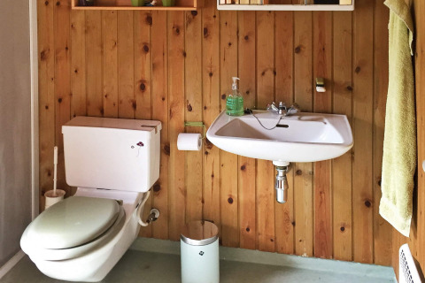Salle de bain avec murs en bois, toilettes et lavabo au lodge Seaside Serenity à Snogebaek, Danemark.
