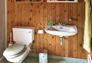 Badkamer met houten muren, toilet en wastafel bij Seaside Serenity in Snogebaek, Denemarken.