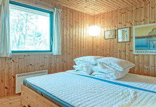 Accogliente camera da letto in legno con letto grande, finestra e quadri in Seaside Serenity a Snogebaek.