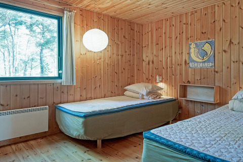 Slaapkamer met twee eenpersoonsbedden, houten wanden, groot raam en eenvoudige inrichting in Snogebaek.