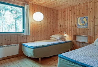 Dormitorio con dos camas individuales, paredes de madera, gran ventana y decoración sencilla en Snogebaek.