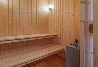 Sauna de madera tradicional con bancos y estufa de piedras en Seaside Serenity en Snogebaek, Dinamarca.