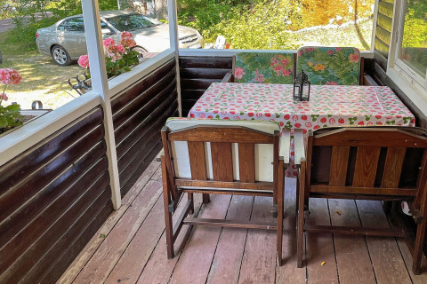 Acogedora terraza con muebles de madera y flores en casa de vacaciones para 6 personas en Rimforsa, Suecia.
